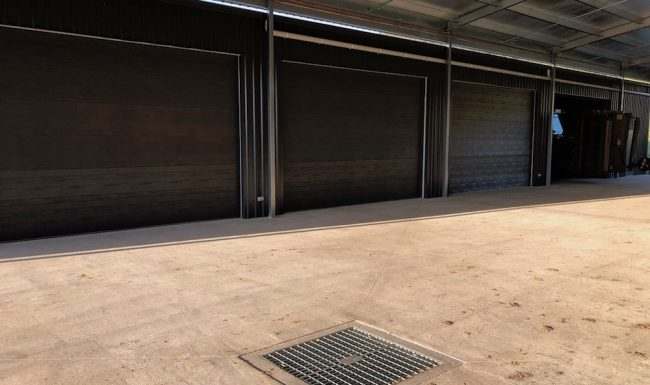 Multiple dark roller doors installed across a large shed