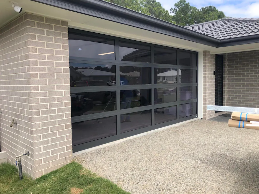 Black sectional garage door with clear aluminium window panels installed by T3 Garage Doors