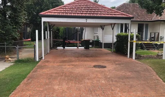 Open tile-roofed carport with a brick-paved driveway, before a door was fitted