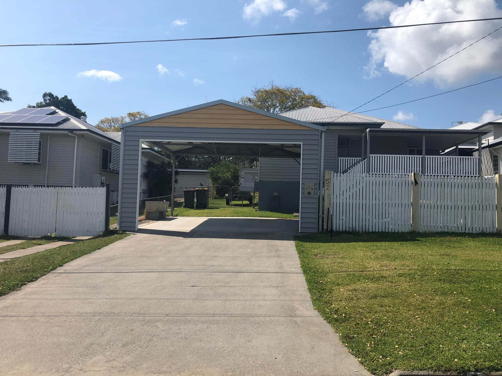 Open carport on a Brisbane weatherboard home with a yellow gable and white picket fence, before a door was fitted