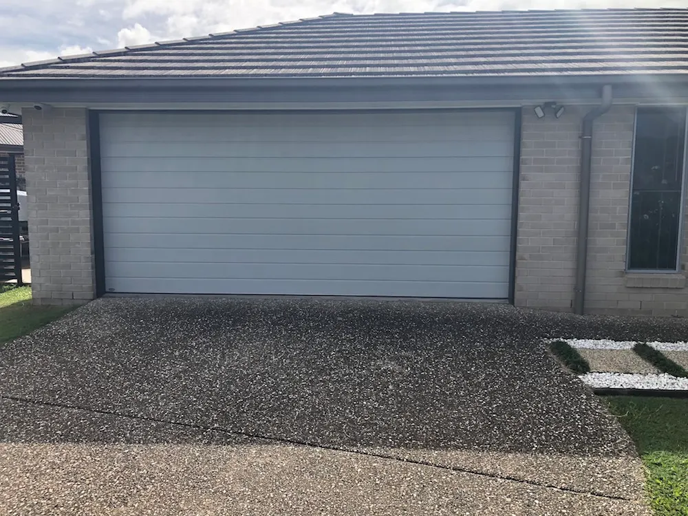Replacement Steel-Line Slimline garage door in a light Shale finish on a brick home