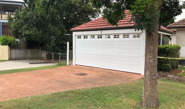 White raised-panel garage door with top windows on a tile-roofed garage